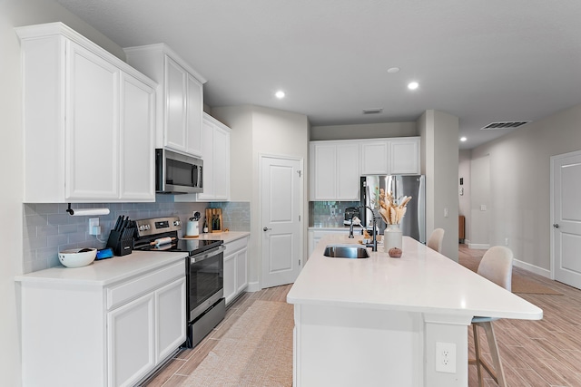 200 SW Pomeroy St, Stuart, FL 34997 - kitchen featuring stainless steel appliances, a sink, a kitchen breakfast bar, backsplash, and a center island with sink
