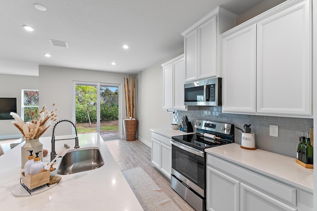 200 SW Pomeroy St, Stuart, FL 34997 - kitchen featuring stainless steel appliances, a sink, light countertops, decorative backsplash, and recessed lighting