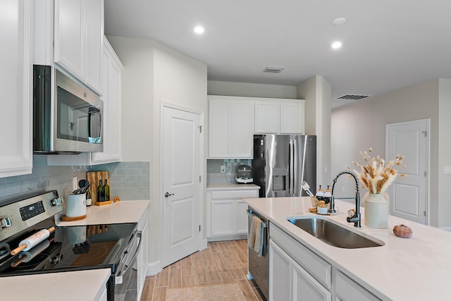 kitchen with stainless steel appliances, sink, light hardwood / wood-style flooring, white cabinets, and decorative backsplash