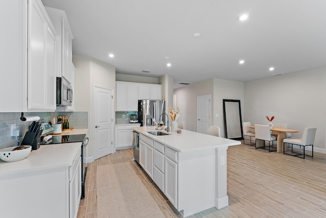 200 SW Pomeroy St, Stuart, FL 34997 - kitchen with appliances with stainless steel finishes, a sink, backsplash, white cabinets, and a center island with sink