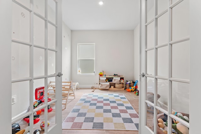 recreation room featuring french doors and light hardwood / wood-style floors