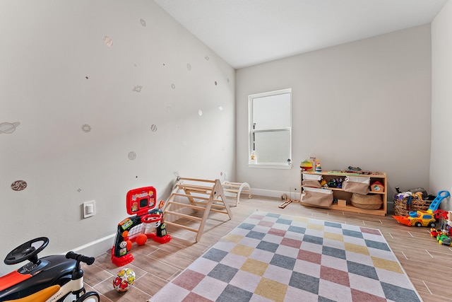 recreation room featuring light wood-type flooring and vaulted ceiling