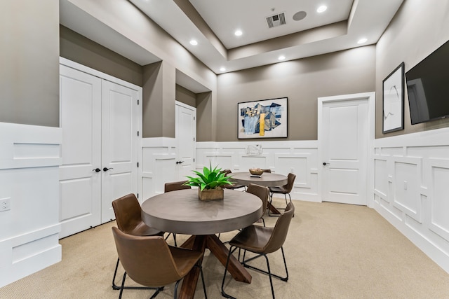 dining area featuring light colored carpet and a raised ceiling