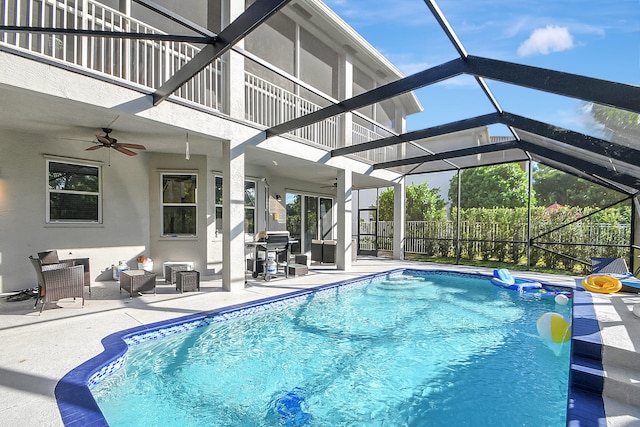 view of swimming pool with glass enclosure, a patio, and ceiling fan