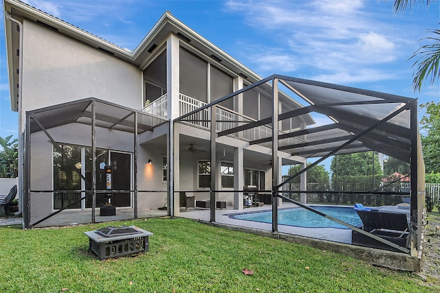 rear view of property featuring a lawn, glass enclosure, and a patio area