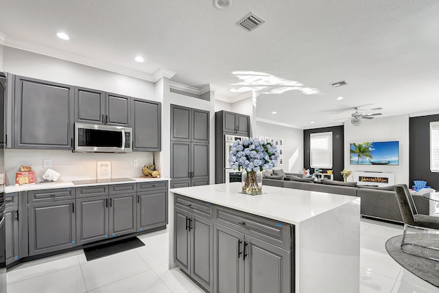 kitchen with gray cabinetry, light tile patterned flooring, crown molding, a kitchen island, and ceiling fan