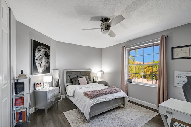 bedroom featuring dark wood-type flooring, a textured ceiling, and ceiling fan