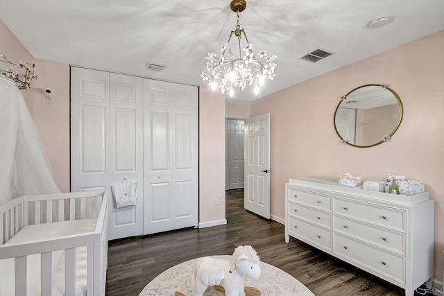 bedroom featuring a closet, a nursery area, a notable chandelier, and dark hardwood / wood-style floors