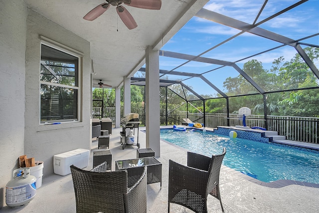 view of swimming pool with glass enclosure, pool water feature, ceiling fan, and a patio