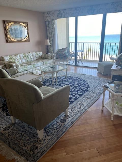 living room featuring a water view, a healthy amount of sunlight, a textured ceiling, and wood-type flooring