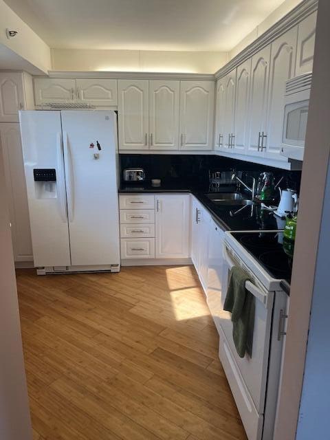 kitchen featuring white cabinets, white appliances, sink, and light hardwood / wood-style flooring