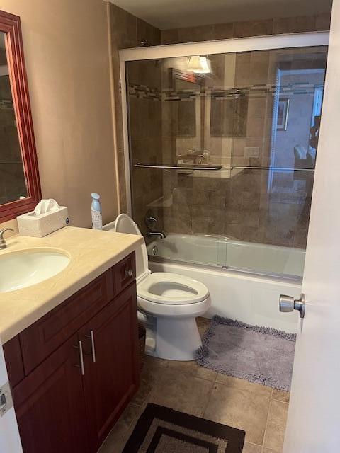 full bathroom with tile patterned floors, vanity, toilet, and enclosed tub / shower combo