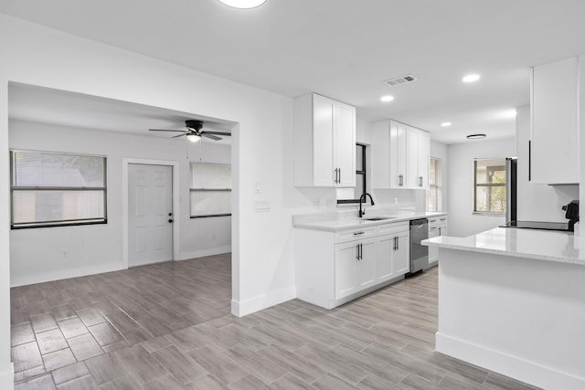 kitchen featuring white cabinets, sink, stainless steel dishwasher, ceiling fan, and light wood-type flooring