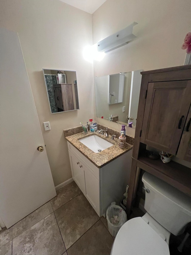 bathroom with toilet, vanity, and tile patterned floors