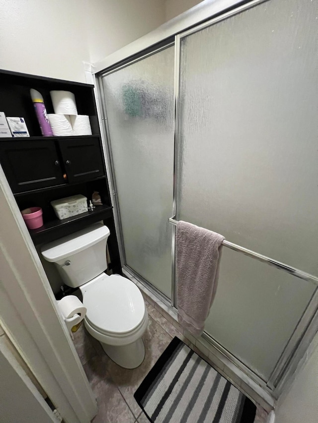 bathroom featuring tile patterned floors, toilet, and an enclosed shower