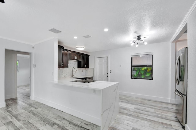 kitchen with light hardwood / wood-style floors, kitchen peninsula, light stone counters, and stainless steel fridge