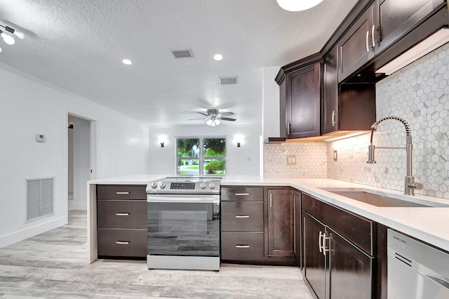 kitchen with stainless steel appliances, light wood-type flooring, a textured ceiling, dark brown cabinets, and sink