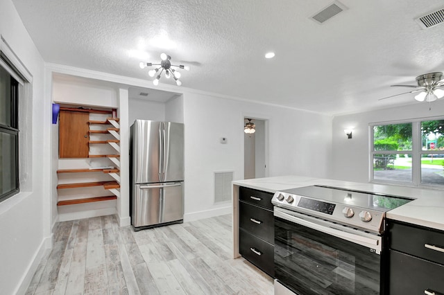 kitchen with a textured ceiling, appliances with stainless steel finishes, ornamental molding, and light hardwood / wood-style floors