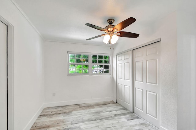 unfurnished bedroom with ornamental molding, a closet, light wood-type flooring, and ceiling fan