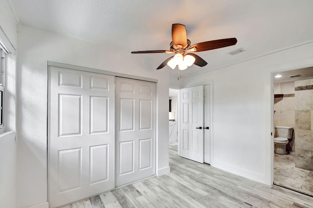 unfurnished bedroom featuring light hardwood / wood-style flooring, a closet, ceiling fan, and ensuite bath