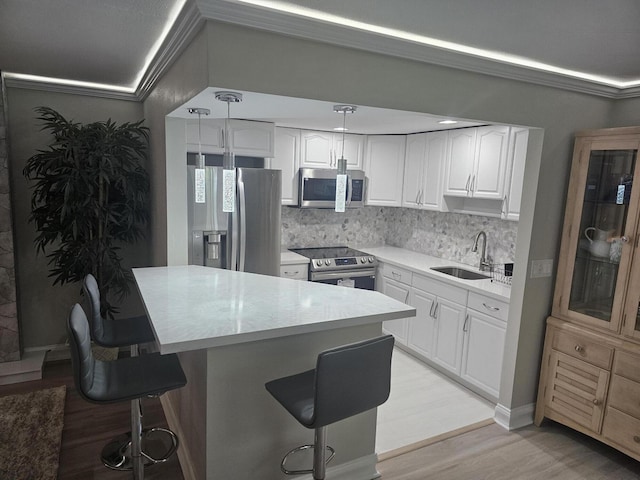 kitchen featuring light wood finished floors, a breakfast bar area, decorative backsplash, appliances with stainless steel finishes, and a sink