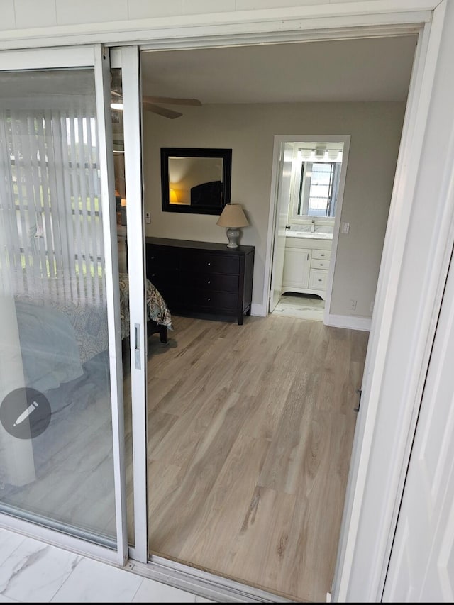 interior space with a stall shower, baseboards, a ceiling fan, wood finished floors, and vanity