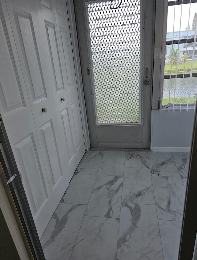 doorway featuring a water view and marble finish floor