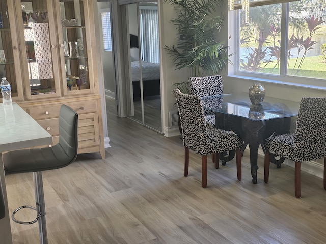 dining space featuring light wood finished floors, baseboards, and visible vents