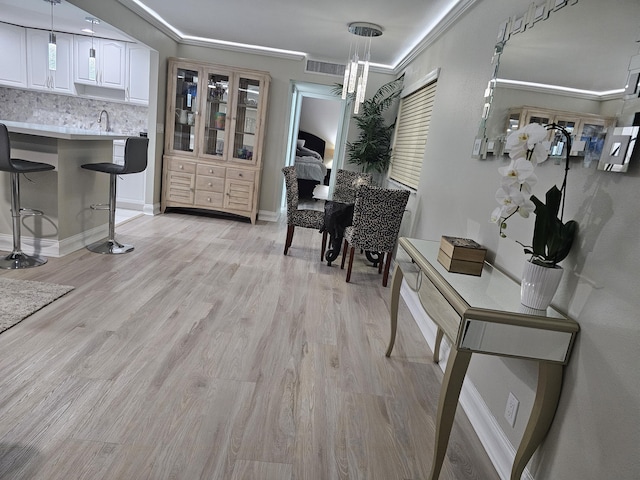 dining room with ornamental molding, light wood-type flooring, visible vents, and baseboards