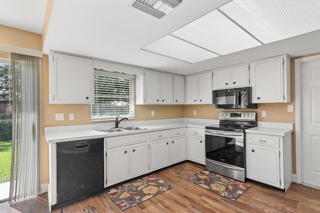 kitchen with a wealth of natural light, white cabinetry, black appliances, and dark hardwood / wood-style flooring