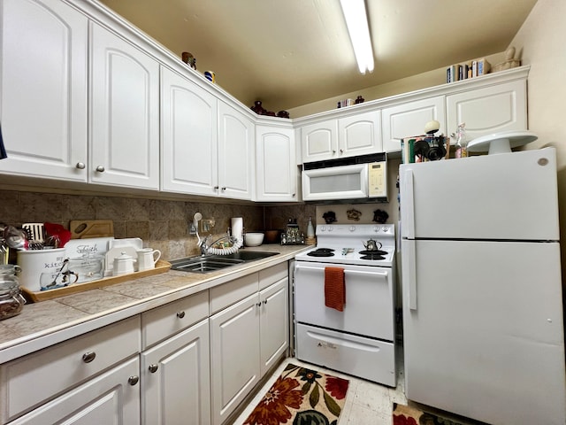 kitchen with tile countertops, sink, backsplash, white cabinetry, and white appliances