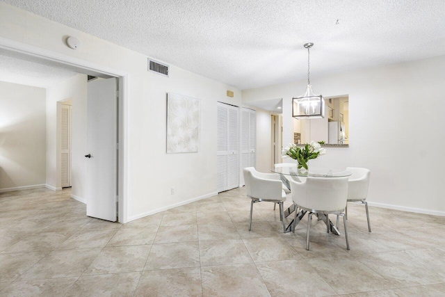 dining room featuring a chandelier, a textured ceiling, and light tile patterned floors