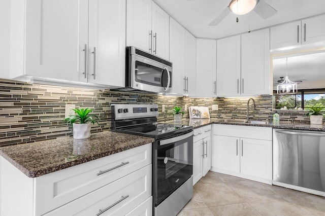 kitchen with white cabinetry, sink, appliances with stainless steel finishes, dark stone countertops, and backsplash