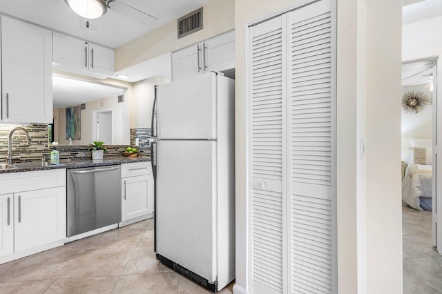 kitchen with stainless steel dishwasher, white cabinetry, white fridge, and sink