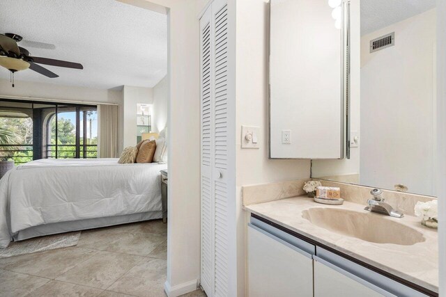 tiled bedroom with ceiling fan, a textured ceiling, and sink