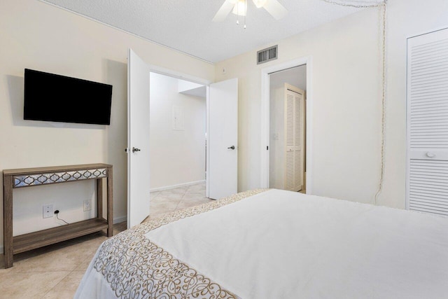 bedroom with ceiling fan, a textured ceiling, and light tile patterned floors