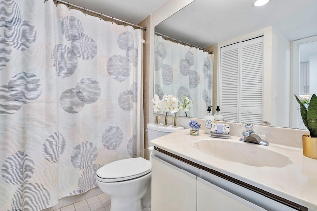 bathroom with toilet, vanity, and tile patterned flooring