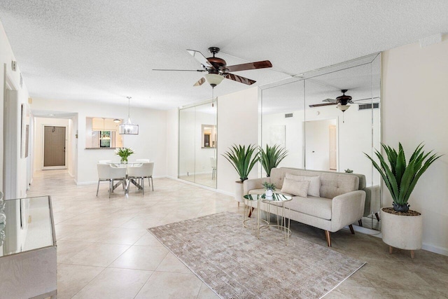 living room featuring a textured ceiling, ceiling fan, and light tile patterned floors