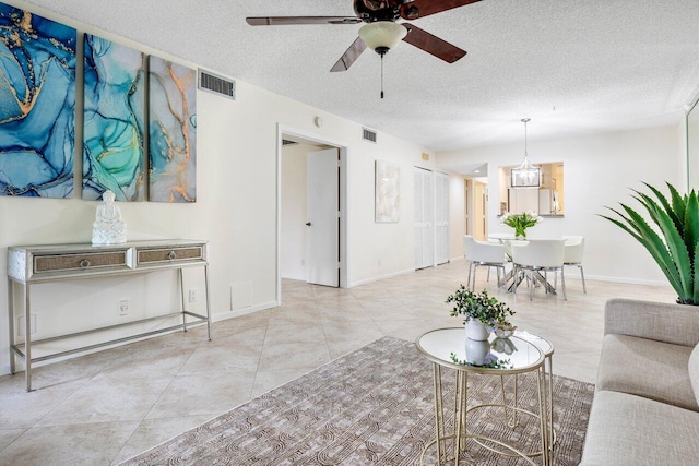 living room featuring a textured ceiling, light tile patterned floors, and ceiling fan