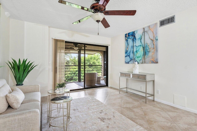 living room featuring ceiling fan, a textured ceiling, and light tile patterned floors