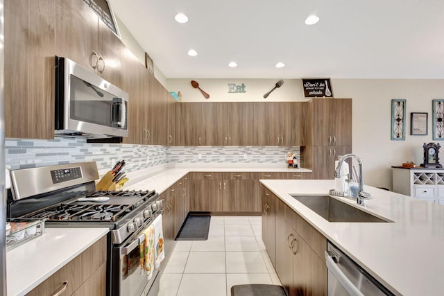 kitchen with stainless steel appliances, light tile patterned floors, sink, and backsplash