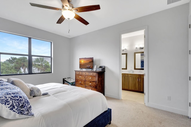 bedroom featuring light colored carpet, ceiling fan, and ensuite bathroom