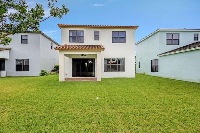 rear view of property with a lawn and ceiling fan