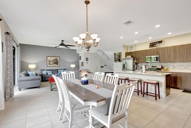 tiled dining area featuring ceiling fan with notable chandelier