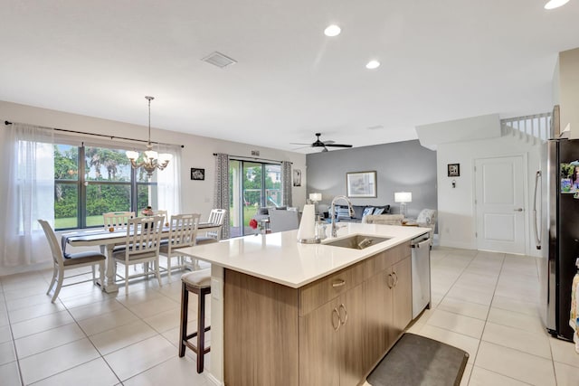 kitchen with ceiling fan with notable chandelier, hanging light fixtures, sink, a kitchen island with sink, and appliances with stainless steel finishes