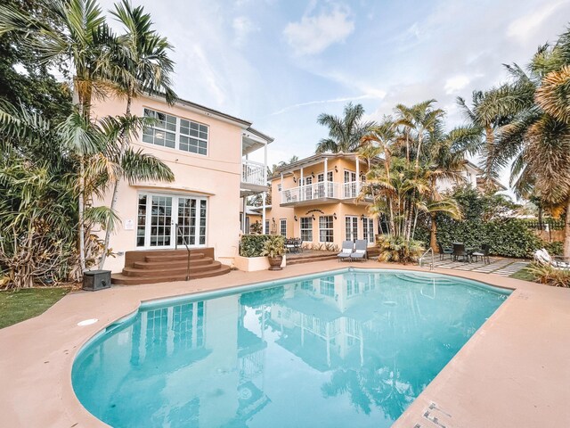 view of pool with a patio area, a water view, and a lawn