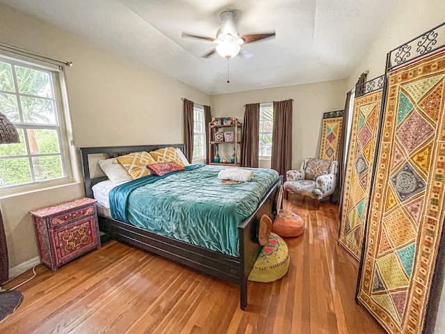 bedroom with ceiling fan, multiple windows, and wood-type flooring