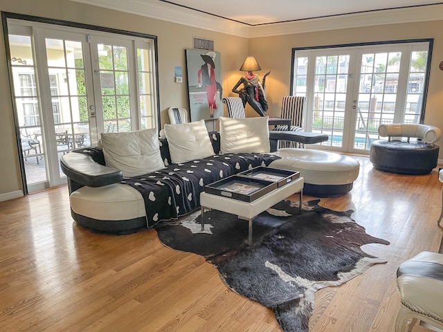 living room with light wood-type flooring, french doors, and ornamental molding