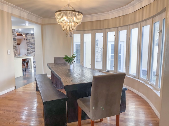 dining room with ornamental molding, hardwood / wood-style floors, a wealth of natural light, and a chandelier