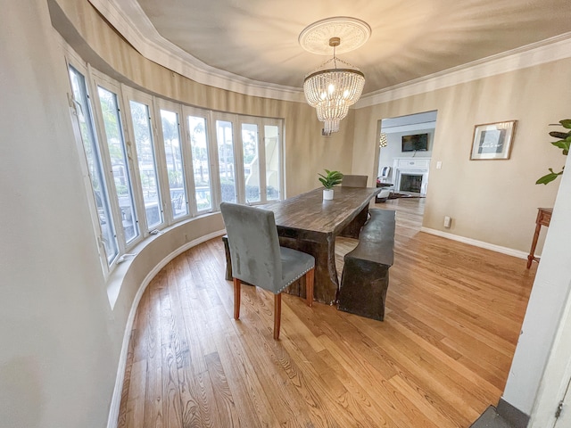 dining area with light wood-type flooring, an inviting chandelier, and crown molding